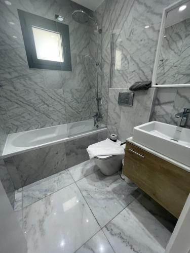 een badkamer met een bad, een toilet en een wastafel bij Pafia 2, Apartment 202 in Paphos City