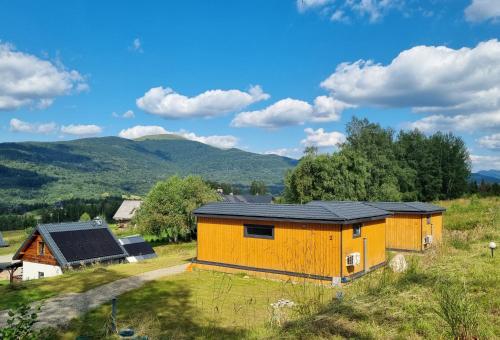 ein Haus auf einem Feld mit Bergen im Hintergrund in der Unterkunft VIEW of SMEREK- domki z klimatyzacją in Smerek