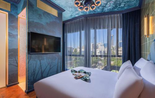 um quarto com uma cama branca e uma grande janela em Play Levontin em Tel Aviv