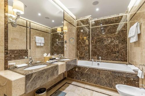 uma casa de banho com 2 lavatórios, uma banheira e um chuveiro em Khreschatyk Hotel em Kiev