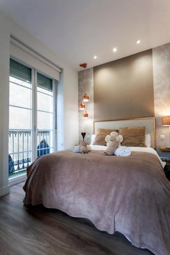 a bedroom with a large bed with two teddy bears on it at Cinco balcones a la Catedral by Unique Rooms in Burgos