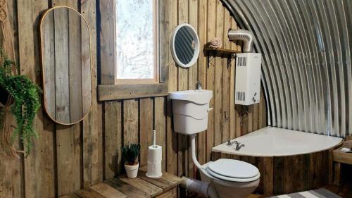 a wooden bathroom with a toilet and a bath tub at 11 Mountain Stream Hot Tub Self Catering in Gordonʼs Bay