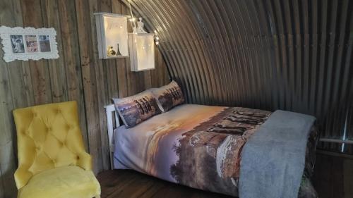 a bedroom with a bed and a yellow chair at 11 Mountain Stream Hot Tub Self Catering in Gordonʼs Bay