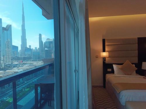 a bedroom with a view of a city from a window at Emirates Grand Hotel in Dubai