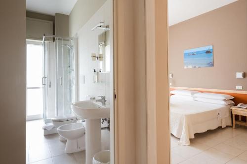 a bathroom with a bed and a sink and a toilet at Hotel Holiday in Vasto