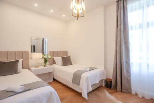 a white bedroom with two beds and a window at Vadkert Major in Sárvár