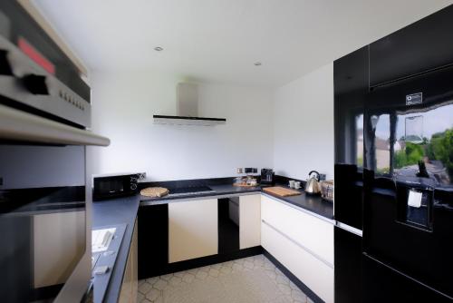 uma cozinha com balcões a preto e branco e um lavatório em Amroth House em Cardiff