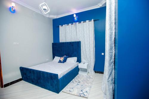 Dormitorio azul con cama y pared azul en Niwa Apartments, en Dar es Salaam