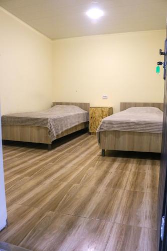 two beds in a room with wooden floors at PIT STOP B&B Guesthouse in Urtsʼadzor