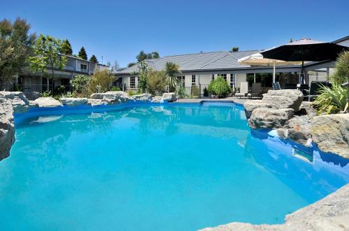 a swimming pool with blue water in a yard at Wai Ora Lakeside Spa Resort in Rotorua