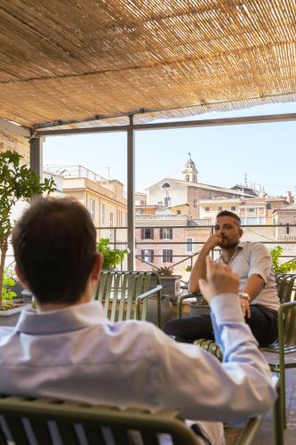 two men sitting in chairs talking on a cell phone at Condominio Monti Boutique Hotel in Rome