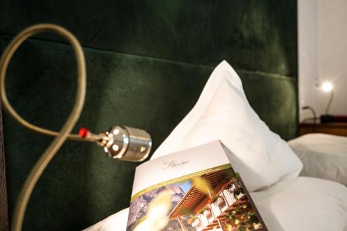 a book on a bed with a lamp on it at Parc Hotel Florian in Siusi