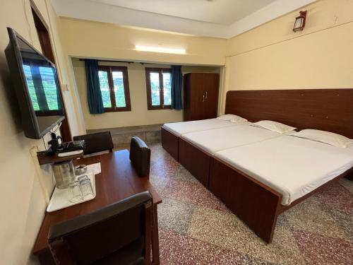 a bedroom with a bed and a desk and a television at Hotel Saluja in Siliguri