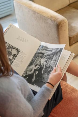a woman sitting on a chair reading a book at Hotel Milani in Rome