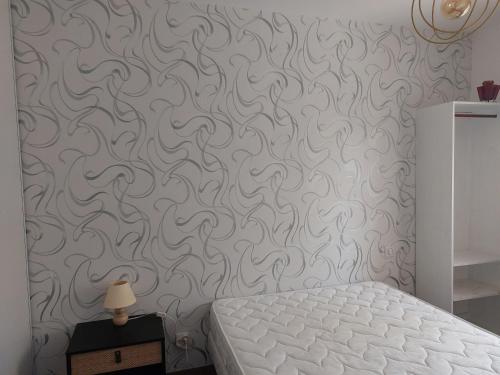 a bedroom with a gray wall with a white bed at Maison au calme proche Cité in Carcassonne