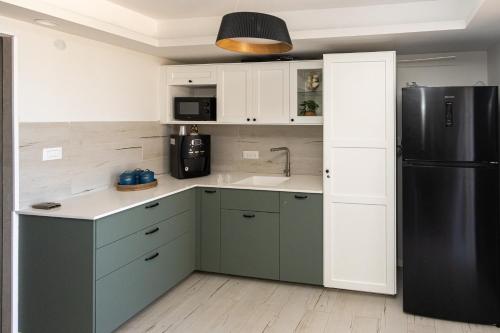 a kitchen with green cabinets and a black refrigerator at בית חוף מושלם עם גקוזי ומרפסת - Beachside Bliss W jacuzzi in Haifa