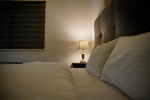 a bedroom with a bed with white sheets and a lamp at Mansi Residence in Wadi Musa