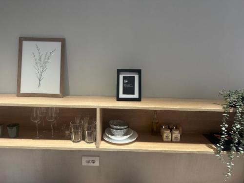 a shelf with a picture and a plate and glasses at EVA Apartment in Novi Sad
