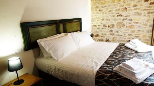 1 dormitorio con 1 cama con sábanas y almohadas blancas en BAGLIO TRAMONTANA, en Gangi