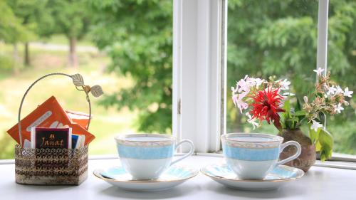 a table with two cups and a vase with flowers at Bellbird in Aso