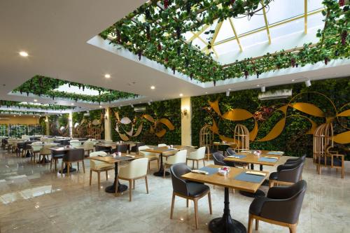 um restaurante com mesas e cadeiras e uma parede de plantas em MerPerle Crystal Palace em Cidade de Ho Chi Minh