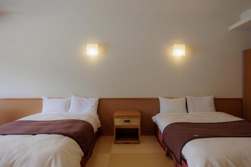 two beds sitting next to each other in a room at Kifuno Sato in Mimasaka