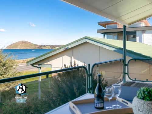 a table with a bottle of wine on a balcony at Beautiful Sea Front 3BR with Great Views in Encounter Bay