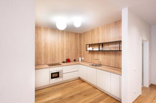 uma cozinha com armários brancos e paredes de madeira em Odilia - Historic City Apartments - center of Brixen, WLAN and Brixencard included em Bressanone