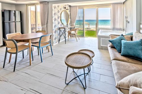 a living room with a couch and a table and chairs at בית חוף מושלם עם גקוזי ומרפסת - Beachside Bliss W jacuzzi in Haifa