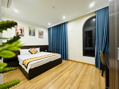 ハロンにあるHưng Nguyễn Hotelのベッドと青いカーテンの窓がある寝室