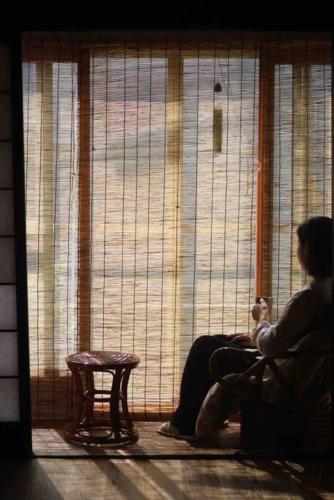 a woman sitting in a chair in front of a window at Aioi Yanto 一日一組限定古民家宿 in Otaru