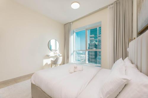 sypialnia z białym łóżkiem i oknem w obiekcie Charming Condo With Balcony In The Heart of JLT w Dubaju