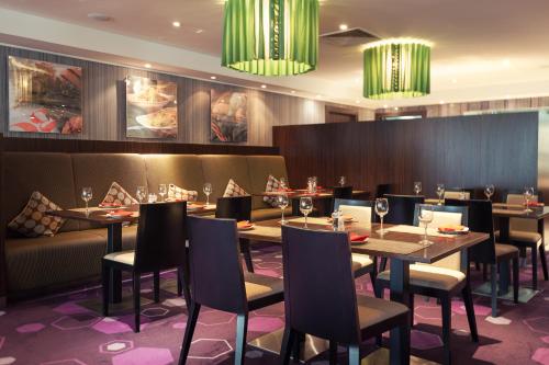 a dining room with tables and chairs and chandeliers at Park Inn by Radisson Hotel Astana in Astana