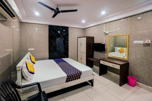 1 dormitorio con cama, escritorio y espejo en OYO Hotel Sri Balaji, en Vijayawāda