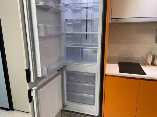 an empty refrigerator with its door open in a kitchen at For you House in Daegu