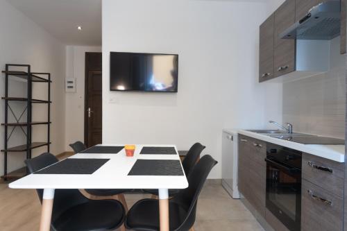 une cuisine avec une table blanche et des chaises noires dans l'établissement Appartement moderne et élégant quartier Saint-Jean Perpignan, à Perpignan
