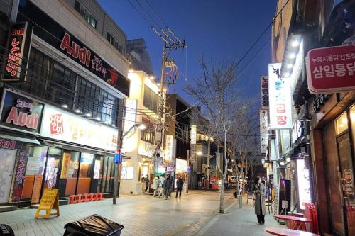 a city street at night with people walking down the street at For you House in Daegu