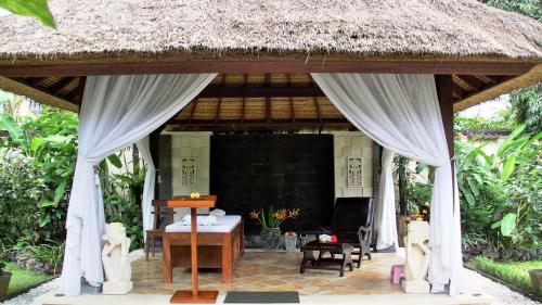 a pavilion with a table and chairs in a garden at Nusa Indah Candidasa in Candidasa