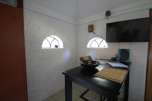 a dining room with a table and two windows at Karin's kruidenhoeve appartement Goudsbloem in Lutten
