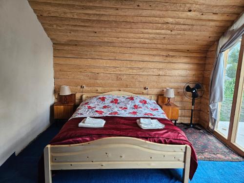 a bedroom with a bed with a wooden wall at Guest House Aleksandre in T'mogvi