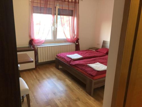 - une chambre avec un lit doté de draps rouges et une fenêtre dans l'établissement Prenočišča Kovač, à Beltinci