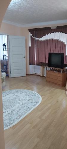 an empty living room with a television and a wooden floor at 2-х комнатная квартира in Balqash