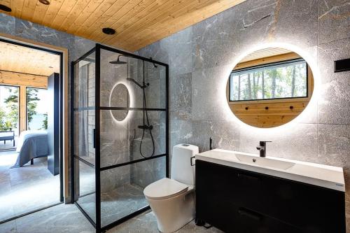 La salle de bains est pourvue de toilettes, d'un lavabo et d'un miroir. dans l'établissement Saunamäki Resort K - Luxury Designer Seafront Villa, à Salo