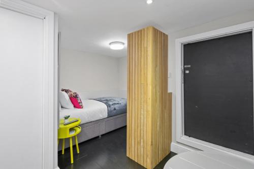 a bedroom with a bed and a yellow chair next to a window at Unique single occupancy studio in London