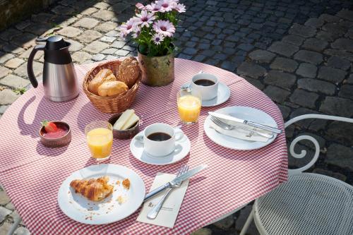 uma mesa rosa e branca com comida e bebidas em Hotel Der Grischäfer em Bad Emstal