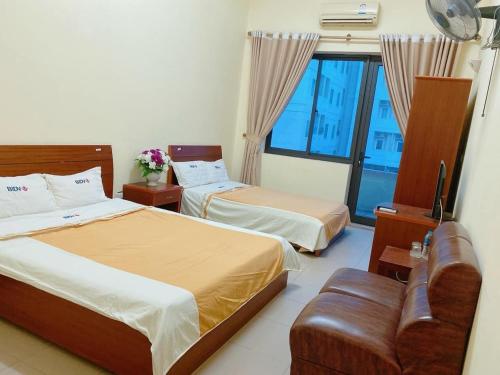 una camera d'albergo con due letti e una finestra di BIDV HOTEL CỬA LÒ a Dong Quan
