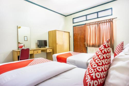 Habitación de hotel con 2 camas y escritorio en OYO 1636 Wisma Kuta Karang en Lhokseumawe