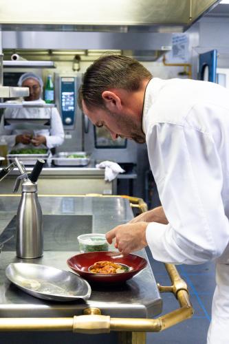 a chef preparing a dish in a kitchen at Sofitel Marseille Vieux-Port in Marseille