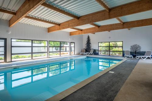 - une piscine d'eau bleue dans un bâtiment avec fenêtres dans l'établissement Logis Auberge De La Foret, à Le Gâvre