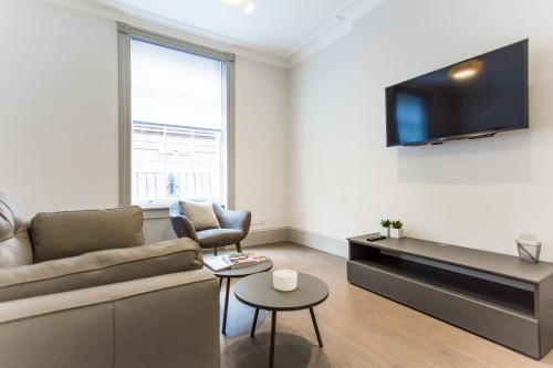 a living room with a couch and a tv at Soho Luxury 1 Bedroom Apartment by Concept Apartments in London